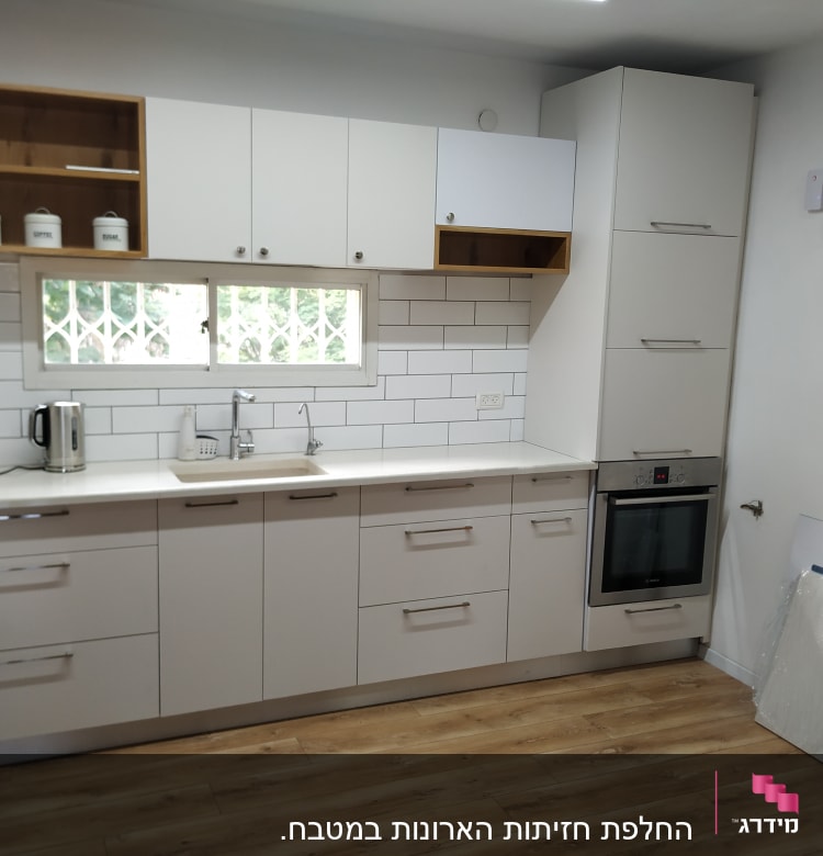 מטבח מודרני עם ארונות לבנים ותנור בילט אין